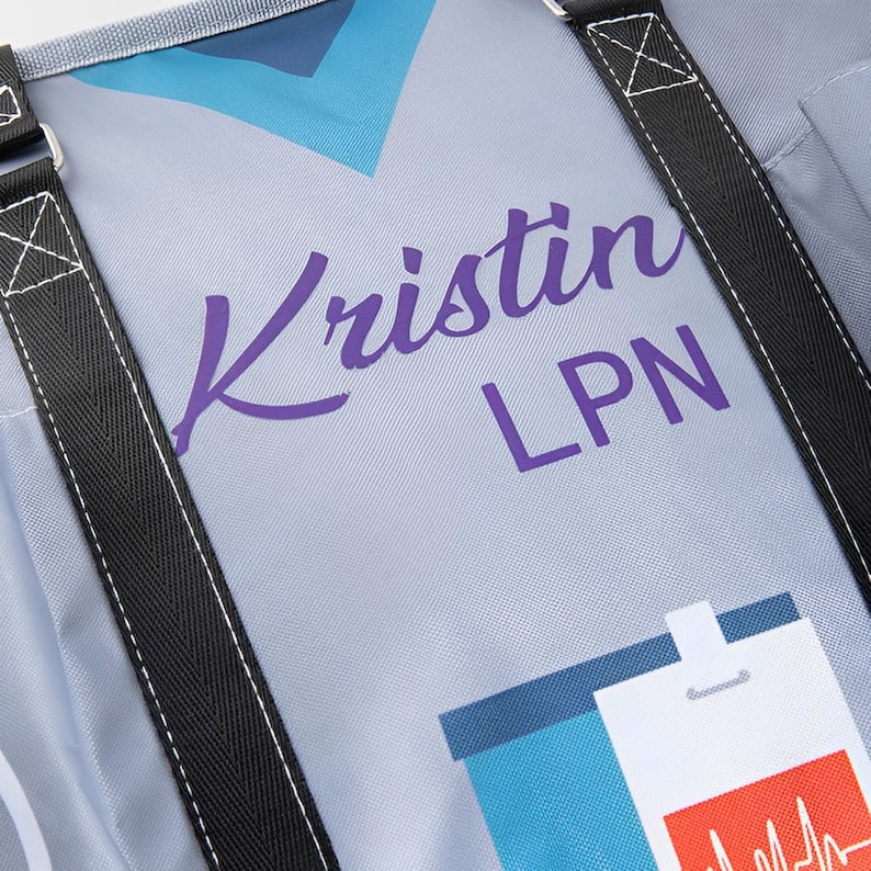 May include: A gray canvas tote bag with black straps. The bag has a purple inscription that says "Kristin LPN" and a blue and white graphic of a stethoscope.