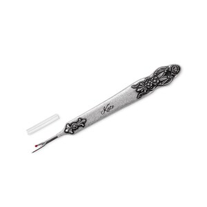 A metal tool with a sharp tip and a hook that can cut threads and seams. The tool can be customized with a name engraved on the handle. It is a vintage style sewing gift for tailors, seamstresses, or fashion designers.
