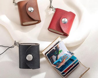 May include: Miniature leather photo albums in brown, red, and black, each with a silver snap closure and a black lanyard. One album is open, displaying colorful photos. These small albums are ideal for carrying cherished memories.