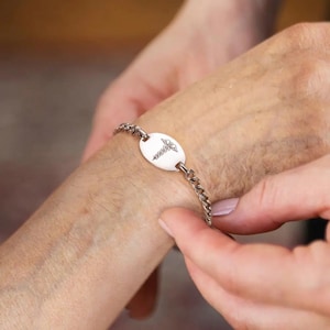 May include: A silver medical alert bracelet with a round charm featuring a caduceus symbol.
