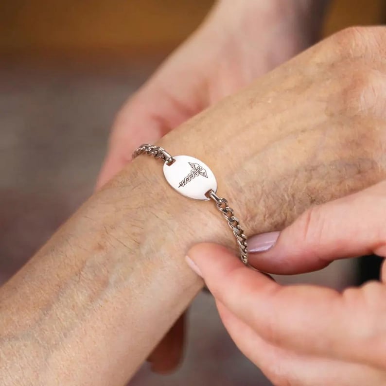 May include: A silver medical alert bracelet with a round charm featuring a caduceus symbol.