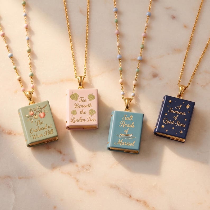 May include: Four gold-tone necklaces with book-shaped pendants in sage green, light pink, dusty blue, and navy blue. Each pendant features gold text and illustrations. The chains are adorned with small, multi-colored pastel beads along the links.