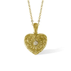 May include: A gold heart-shaped locket necklace with a diamond accent. The locket has an intricate floral design.
