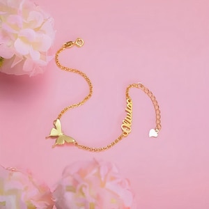 Könnte beinhalten: Goldkette Armband mit einem Schmetterlingsanhänger und einem Namensschild mit der Aufschrift "Olivia".