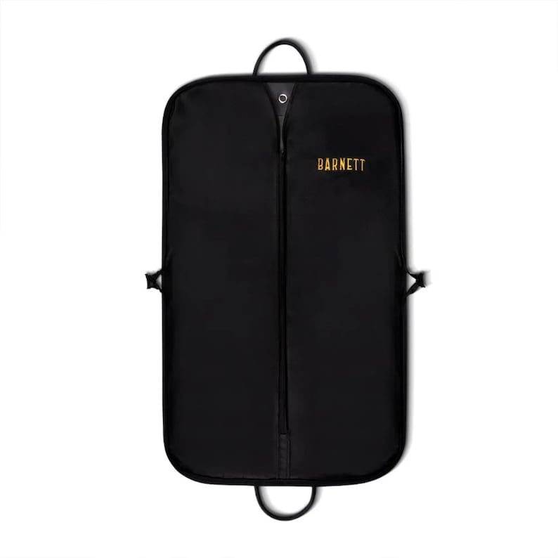 Puede incluir: Funda de ropa negra con cremallera de largo completo, asa superior e inferior. La palabra "BARNETT" est&aacute; impresa en letras doradas en la parte delantera. La bolsa tiene forma rectangular con esquinas redondeadas y clips laterales.