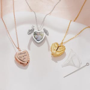 May include: Three heart-shaped locket necklaces in rose gold, silver, and gold. The rose gold locket has the inscription "Always by your side." The silver locket opens to reveal a photo. The gold locket has a wing design.