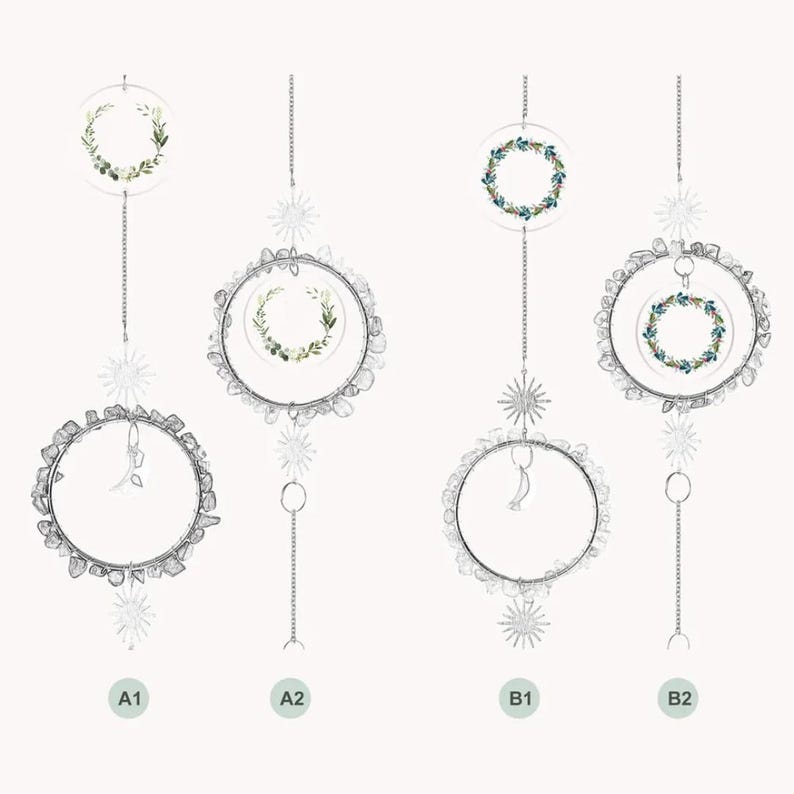 May include: Four hanging suncatchers with clear circular frames and decorative elements. Two feature wreaths of green leaves, while the other two have blue and green floral wreaths. Each is suspended by a chain with star and moon accents.