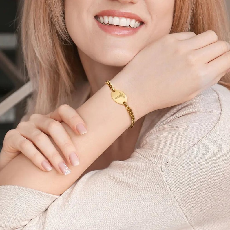 May include: A gold chain bracelet with a round pendant featuring a medical symbol. The pendant is engraved with the word "Nurse".