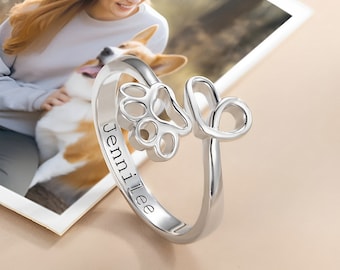 Puede incluir: Anillo de plata con un diseño de huella de pata y corazón. El anillo está grabado con el nombre "Jennilee".