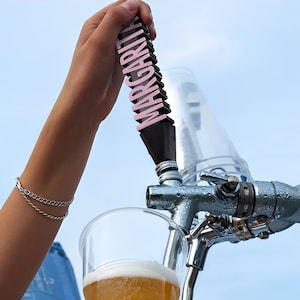 May include: A person pouring a beverage from a tap with a black and pink handle that says "MARGARITA" on it into a clear plastic cup.