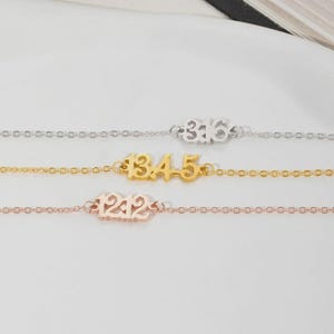 Puede incluir: Tres delicadas pulseras de cadena en plata, oro y oro rosa. Cada pulsera presenta una fecha en números: 316, 1345 y 1212. Las pulseras se muestran sobre una superficie blanca.