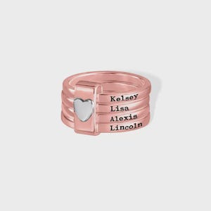 Pu&ograve; includere: Anello impilabile in oro rosa con un cuore argentato. L'anello presenta i nomi Kelsey, Lisa, Alexis e Lincoln incisi sulle fasce. Un gioiello personalizzato.