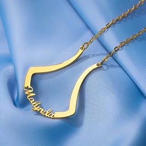 Puede incluir: Collar de oro con un diseño abierto y curvo que deletrea el nombre "Madynda".