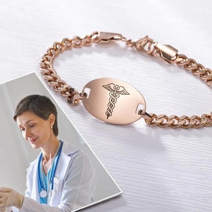 May include: A rose gold medical ID bracelet with a curb chain and an oval tag engraved with the caduceus symbol.