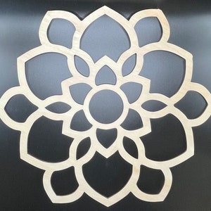 May include: A wooden mandala with a circular design featuring intricate cutouts in the shape of overlapping petals. The mandala is light brown and has a natural wood finish.