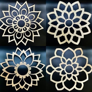 May include: Four decorative wooden wall hangings in the shape of stylized flowers. The flowers are all white and have a detailed design. They are set against a black background.