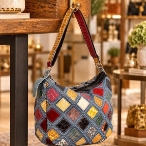 May include: A hobo-style handbag featuring a patchwork design of multi-colored, textured diamond-shaped leather pieces in shades of red, yellow, blue, and black, with a matching shoulder strap and a top zipper closure.
