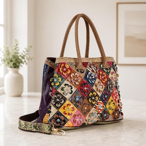 May include: A multi-colored handbag featuring a diamond-patterned exterior with various textured patches, including animal prints and floral appliqués with central crystals. It has two brown top handles and a detachable green snakeskin-patterned strap.