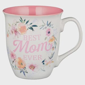 May include: White ceramic mug with a pink interior and handle. The mug is decorated with a floral wreath design in pastel colors and the words "BEST Mom EVER" in pink lettering.