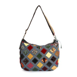 May include: A patchwork shoulder bag with a gray denim base and a variety of colorful diamond-shaped patches. The patches include red, yellow, green, and brown textures. The bag has a brown strap and silver hardware.