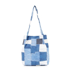 May include: A blue patchwork tote bag with a single strap. The bag is made of different shades of blue denim and has a rectangular shape.