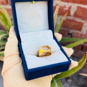 May include: A gold ring with a hexagonal setting. The ring is in a blue velvet box.