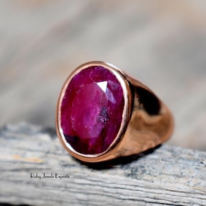 Puede incluir: Un anillo con una gran piedra preciosa de rubí de forma ovalada engastada en una banda de oro rosa.