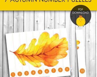 May include: A white paper puzzle with a watercolor illustration of an autumn leaf, divided into sections numbered 1-9. A separate piece is numbered 10. The text "7 AUTUMN NUMBER PUZZLES" is at the top. A PDF download icon is in the upper right.