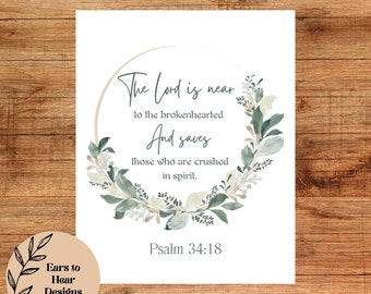 May include: A white printable art print with a green and white floral wreath surrounding a quote from Psalm 34:18. The quote reads "The Lord is near to the brokenhearted And saves those who are crushed in spirit."