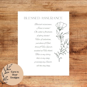 May include: A white print featuring the words "Blessed Assurance" and a poem. The print includes a floral design and the words "Ears to Hear Designs" in a circle in the lower left corner. The background is a wooden surface.