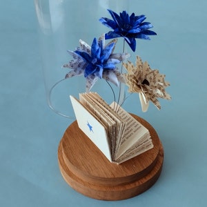 Miniature paper flowers and book in a glass dome