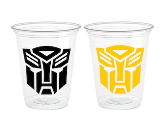 May include: Two clear plastic cups with a Transformers logo. One cup has a black logo, and the other has a yellow logo. The logos are a stylized robot face.