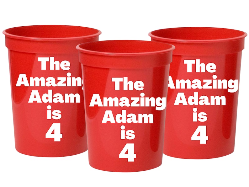 Puede incluir: Tres vasos de pl&aacute;stico rojos con el texto "The Amazing Adam is 4" impreso en ellos.