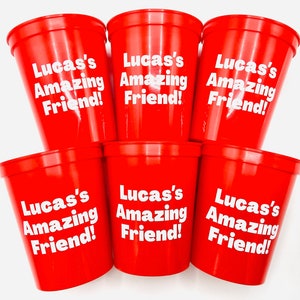 Puede incluir: Seis vasos de pl&aacute;stico rojos con texto blanco que dice "Lucas's Amazing Friend!"