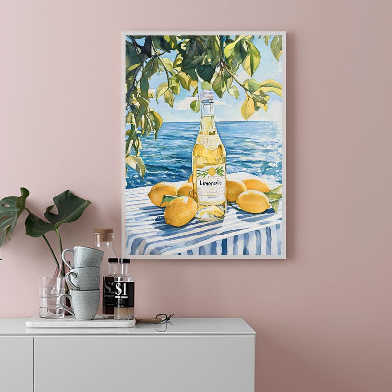 May include: A watercolor painting of a bottle of Limoncello liqueur on a blue and white striped tablecloth with lemons around it. The bottle is in focus and the background is a blurry image of a blue ocean and green leaves.