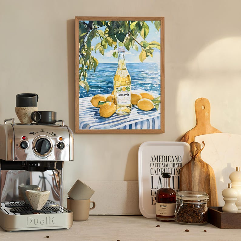 May include: A watercolor painting of a bottle of Limoncello on a blue and white striped tablecloth with lemons around it. The painting is framed in a light wood frame and is hanging on a wall.
