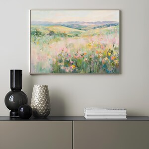 K&ouml;nnte beinhalten: Ein Gem&auml;lde, das ein Feld mit Wildblumen in einer Landschaft zeigt. Das Feld ist mit rosa, gelben und wei&szlig;en Blumen gef&uuml;llt. Der Hintergrund ist ein gr&uuml;ner, h&uuml;geliger H&uuml;gel mit blauem Himmel.