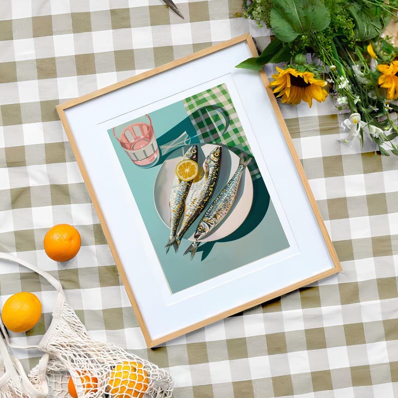May include: A framed print of a still life featuring three whole fish on a white plate with a lemon wedge. The plate is on a turquoise background with a green and white checkered pattern in the corner.