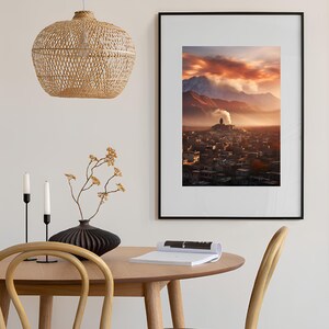 May include: A framed photograph of a city with a mountain range in the background. The city is covered in a layer of fog and the sky is a vibrant orange and pink.