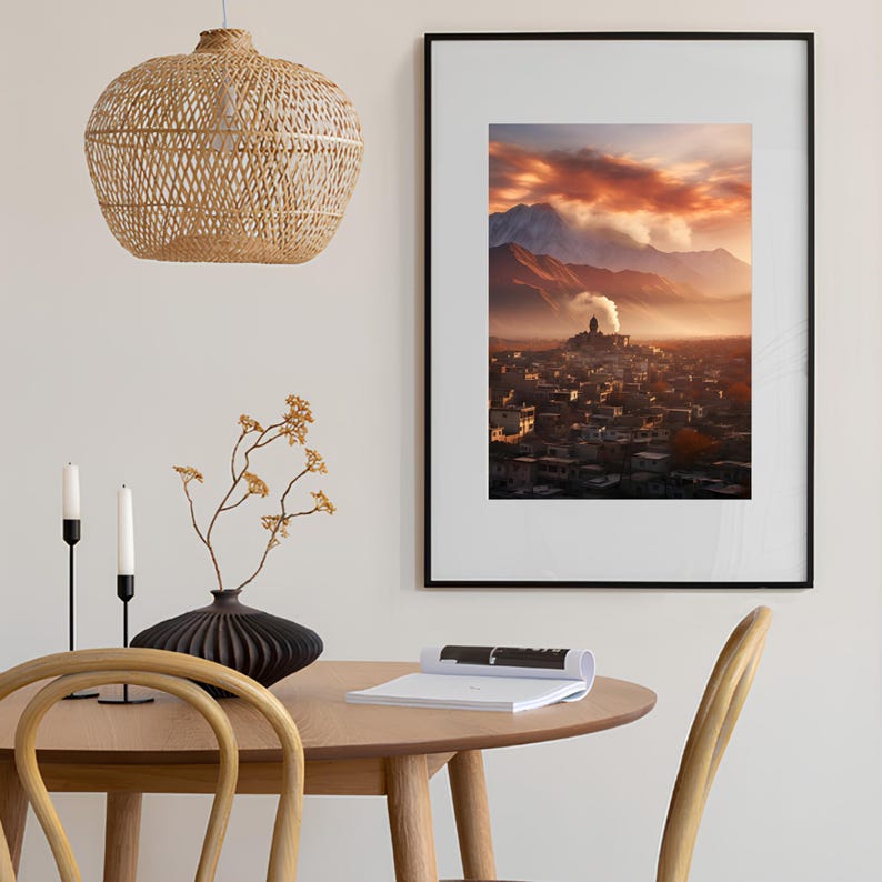 May include: A framed photograph of a city with a mountain range in the background. The city is covered in a layer of fog and the sky is a vibrant orange and pink.