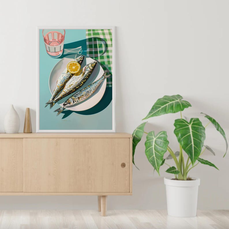 May include: A still life photograph of three whole fish on a white plate with a lemon wedge. The plate is on a blue background with a green and white checkered cloth in the background. A glass of pink liquid is in the upper left corner of the image.