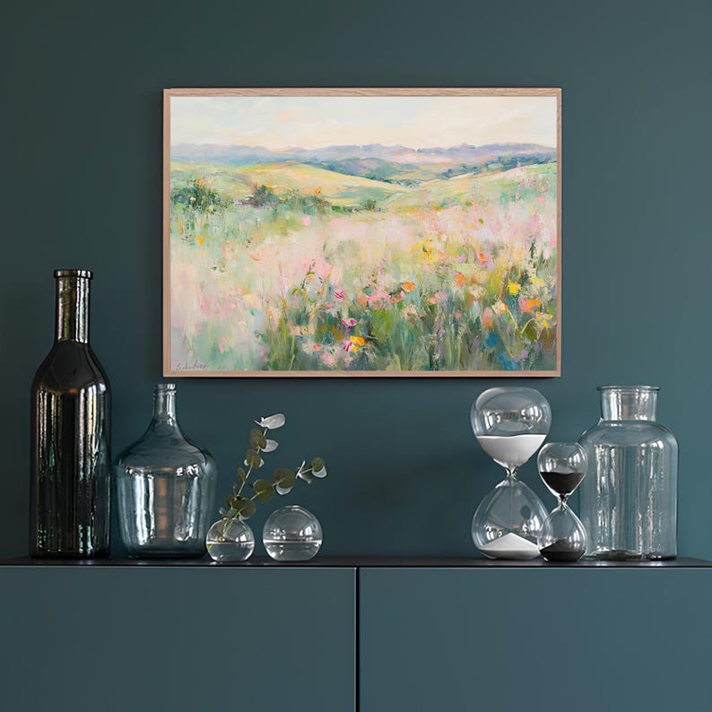 K&ouml;nnte beinhalten: Ein gerahmtes Gem&auml;lde einer Landschaft mit sanften H&uuml;geln und einem Feld voller Wildblumen in Rosa-, Gelb- und Gr&uuml;nt&ouml;nen. Das Gem&auml;lde h&auml;ngt an einer t&uuml;rkisfarbenen Wand, unterhalb befindet sich ein Regal mit einigen Dekoartikeln.