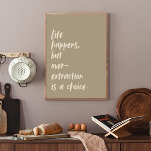May include: A framed print with a beige background and white text that reads "Life happens, but over-extraction is a choice."