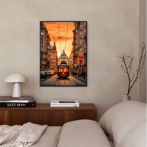 May include: A framed photograph of a red vintage tram traveling down a city street at sunset. The tram is surrounded by buildings and people walking on the sidewalk.