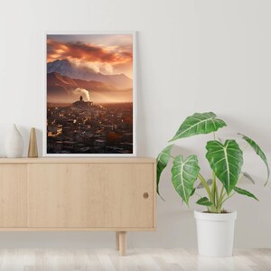 May include: A framed photograph of a mountain village with a red sky and clouds in the background. The village is nestled in a valley with a mountain range in the distance.
