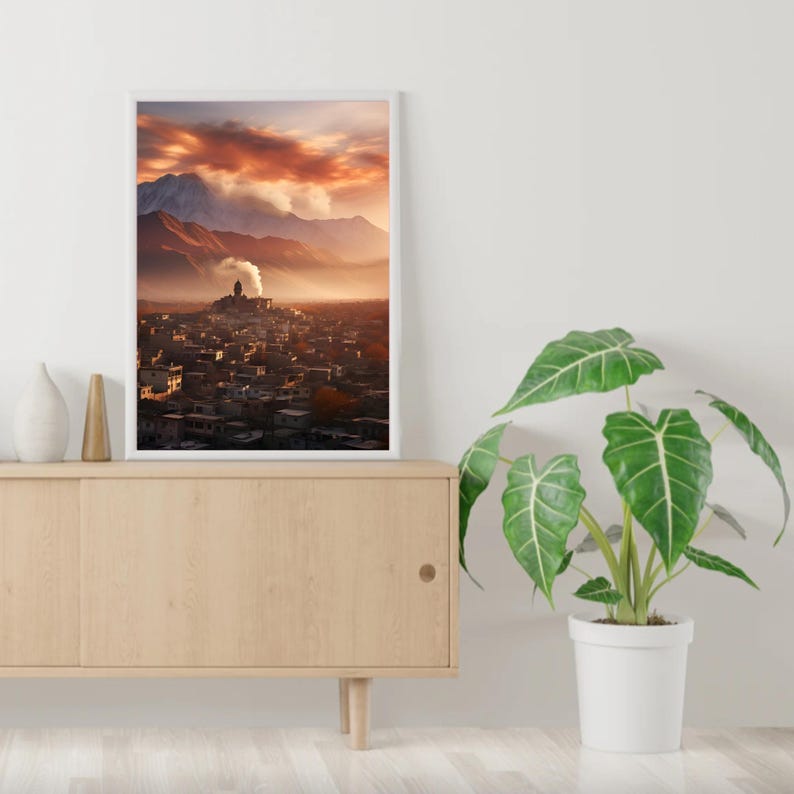 May include: A framed photograph of a mountain village with a red sky and clouds in the background. The village is nestled in a valley with a mountain range in the distance.