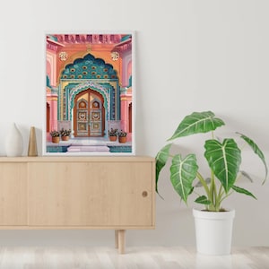 Peut inclure: Une impression encadr&eacute;e d'une porte orn&eacute;e et color&eacute;e avec des d&eacute;tails complexes. La porte est peinte dans des tons de rose, vert et bleu, avec une porte en bois au centre. L'impression est plac&eacute;e contre un mur blanc, avec une plante en pot au premier plan.