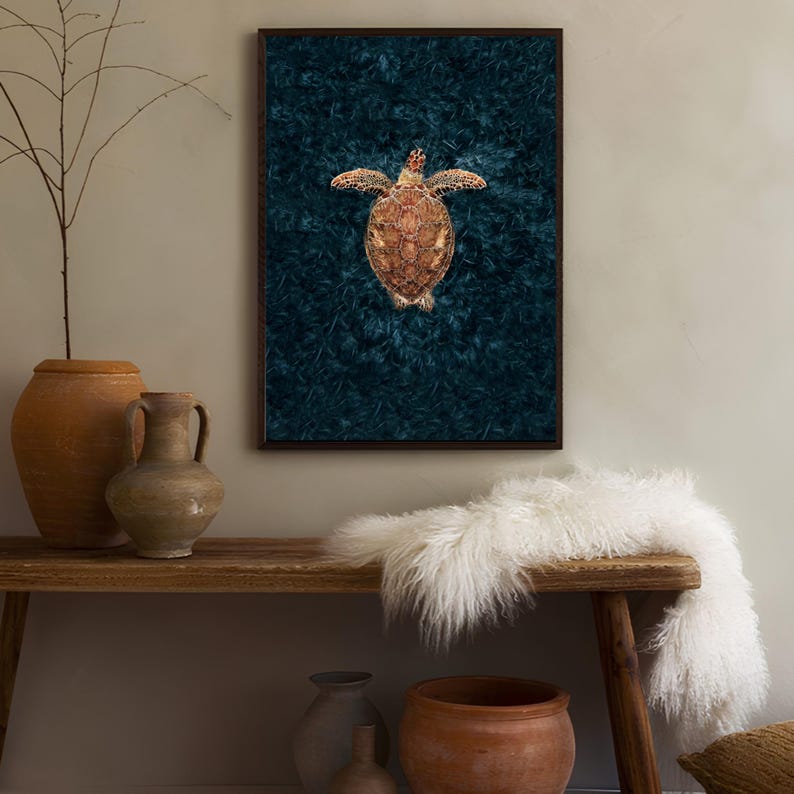 May include: A framed print of a sea turtle swimming in a dark blue ocean. The turtle is facing upwards with its shell visible. The background is a dark blue with a textured pattern.