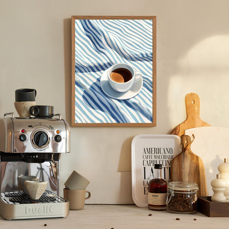 May include: A framed illustration of a cup of coffee on a blue and white striped tablecloth. The cup is white with a brown rim and a brown handle. The coffee is dark brown. The tablecloth is folded over itself and the stripes are visible. The frame is brown wood.