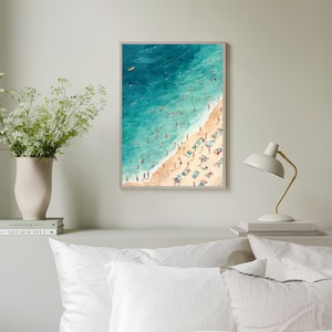 May include: An aerial view of a beach scene with turquoise water and a sandy shore. People are swimming, sunbathing, and relaxing on beach chairs. A small yellow boat is visible in the distance.